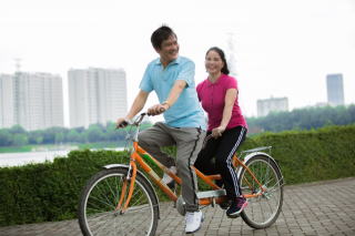 元気にサイクリングする中年夫婦の写真